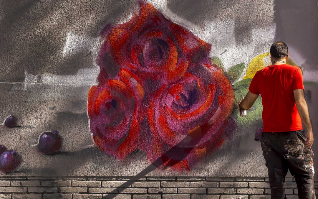 Un hombre haciendo un grafiti de tres rosas en una pared en primavera
