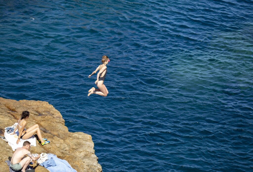 Chica saltando al mar en cala Montgó, una de las playas de Girona con Bandera azul