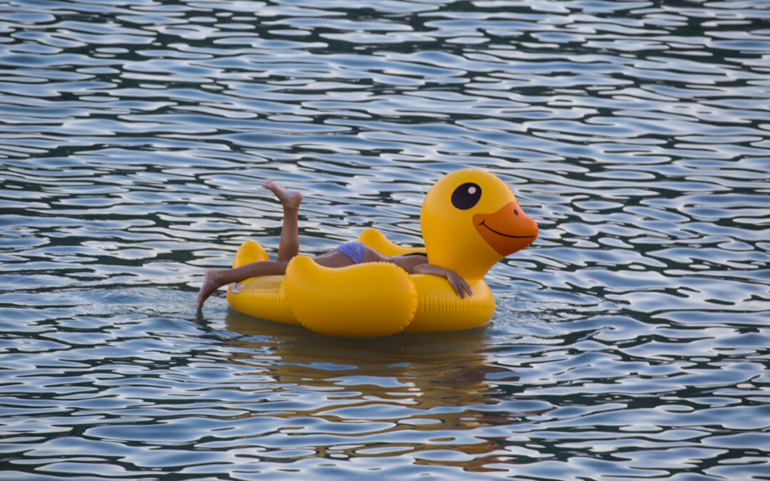 Nena banyant-se amb un flotador en forma d'anec al mar